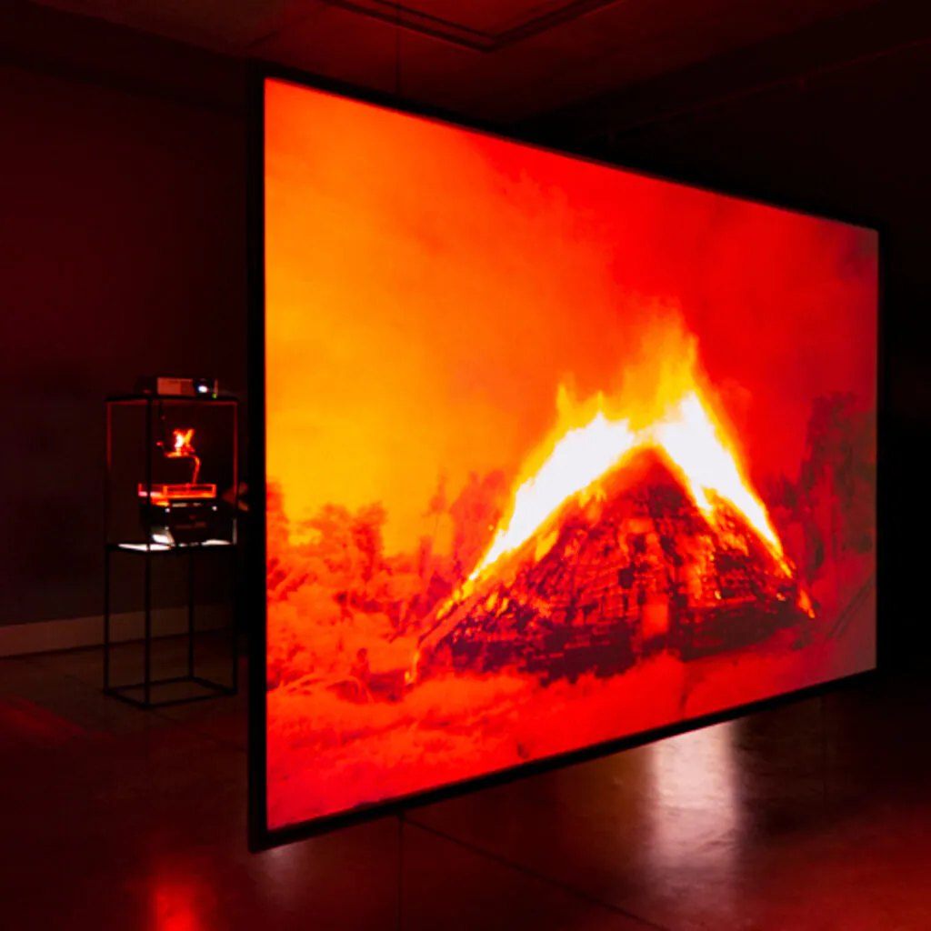 Claudia Andujar, Gisela Motta e Leandro Lima, Yano-a, 2005, Videoinstalação, tela suspensa de retroprojeção, projetor de vídeo, retroprojetor, fotolito, filtro de cor, micro ventilador, aquário e água. Foto: William Gomes.