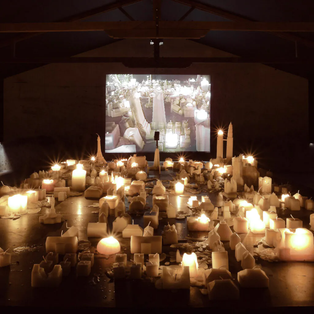Carlos Garaicoa, Ahora Juguemos a Desaparecer (II), 2002, mesa de metal, velas, instalação de vídeo, dimensões variáveis. Foto: Eduardo Eckenfels