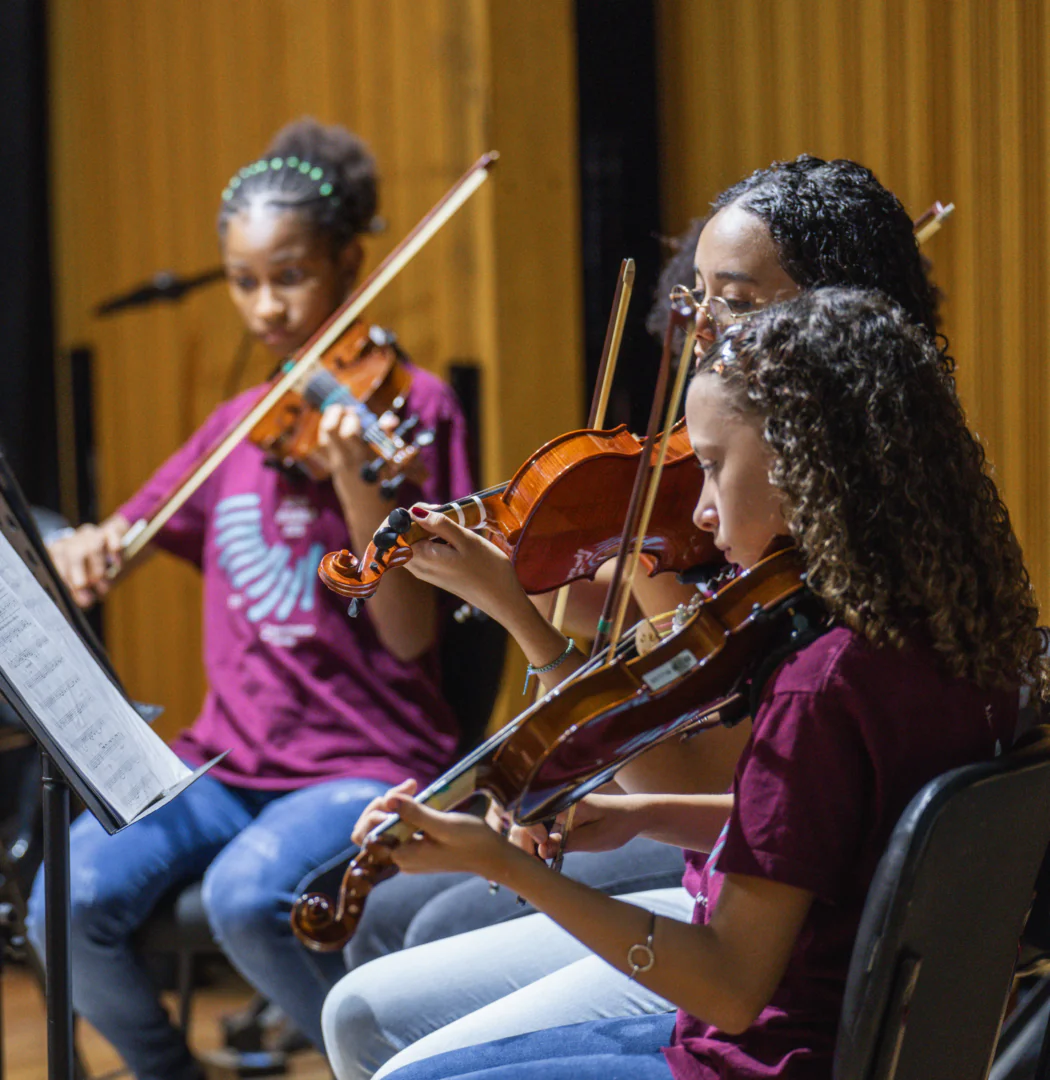 Estudantes e suas famílias conhecem a estrutura da Escola de Música Inhotim e assistem à apresentação de concerto didático com pessoas professoras. 